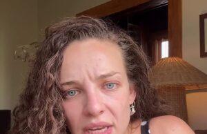 Upset woman with curly hair and blue eyes in a polka dot dress, indoors, emotional expression.