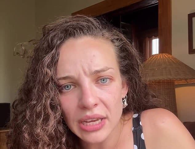 Upset woman with curly hair and blue eyes in a polka dot dress, indoors, emotional expression.