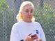 News Room : Amanda Bynes unveils latest body modification after getting lip fillers and dropping almost 30lbs on Ozempic Woman using smartphone outdoors near a fence with greenery in the background.
