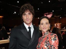 Elegant woman in a vibrant patterned dress standing next to man in a sharp black suit at a formal event.