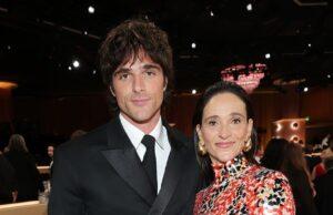 Elegant woman in a vibrant patterned dress standing next to man in a sharp black suit at a formal event.
