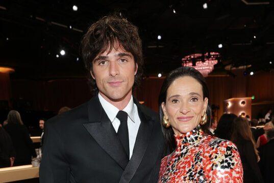 Elegant woman in a vibrant patterned dress standing next to man in a sharp black suit at a formal event.