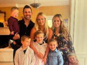 Happy family portrait of parents, kids, and baby celebrating indoors in bright, cozy home.