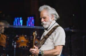 OLD MAN PLAYING GUITAR AT CONCERT, MUSICIAN PERFORMING ON STAGE.