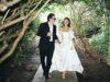 News Room : Brooklyn Beckham’s explosive claim his mother Victoria pulled out of designing Nicola Peltz’s wedding dress at the ‘eleventh hour’ is contradicted by bride’s stylist who said her couture Valentino gown took a YEAR to make Stylish couple walking through lush garden forest in elegant wedding attire, enjoying a romantic moment.