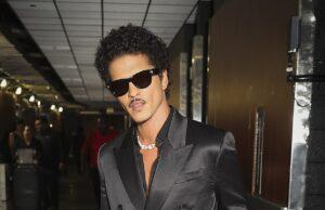 Stylish man in black satin double-breasted suit with sunglasses at airport.