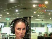 Woman broadcasting live at a radio station studio in a modern office environment.