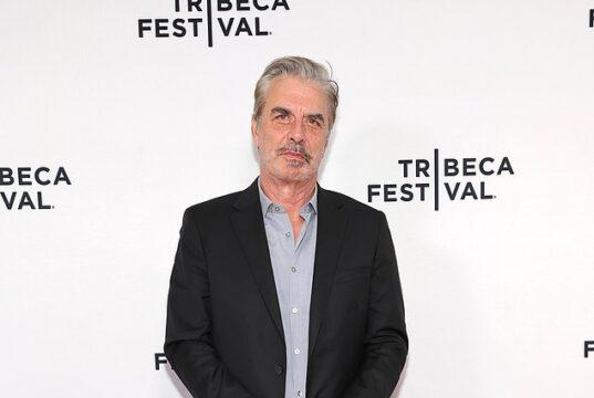 Stylish middle-aged man in black suit at Tribeca Festival red carpet event.