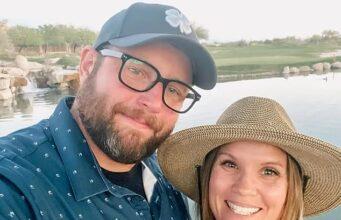 Smiling couple outdoors by water, enjoying the moment on a sunny day.