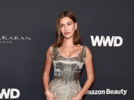 Elegant woman in gold metallic dress at event, posing on red carpet.