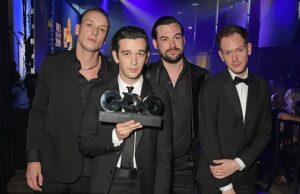 News Room : Have The 1975 split up? Band sends fans into meltdown after deleting Instagram grid and sharing ambiguous farewell post – four years after last album Men in formal suits accepting an award at a ceremony in a nightclub or event hall.