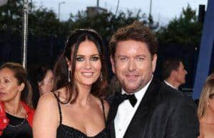 News Room : James Martin’s stunning girlfriend Kim Johnson, 39, ‘CONFIRMS’ her engagement to the TV chef, 53, after he insisted he’d never get married Elegant couple in formal black attire attending a glamorous event, surrounded by other guests.