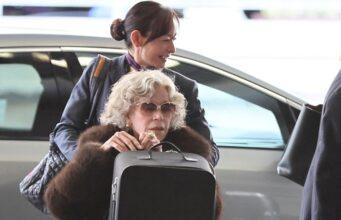 News Room : Jane Fonda, 88, is pushed in wheelchair at airport after Reiner murders left her ‘reeling’ Woman with curly gray hair wearing sunglasses in a wheelchair at the airport, being assisted by a smiling staff member.