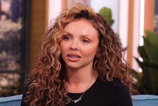 Curly-haired woman speaking passionately on a talk show set.