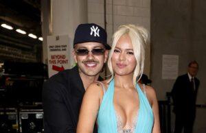 Smiling couple embracing at an indoor event, woman in a striking blue gown with thigh-high slit.