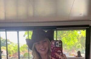 Vibrant woman in polka dot swimsuit and cowboy hat taking mirror selfie indoors at bright, modern space.