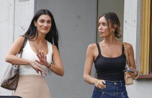 Women having conversation outside a building in casual attire, one gesturing with her hand.