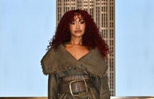 Stylish woman in a textured coat, patterned tights, and fur boots on city rooftop balcony at sunset.