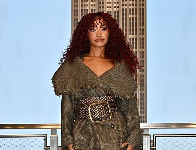 Stylish woman in a textured coat, patterned tights, and fur boots on city rooftop balcony at sunset.