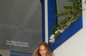 Stylish woman on staircase wearing white outfit with hair and makeup details provided.