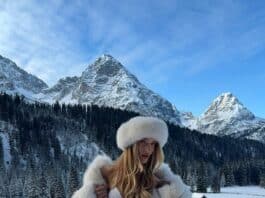 Hot woman in winter landscape in bikini and fur hat, snowy mountains in background, scenic outdoor photo.